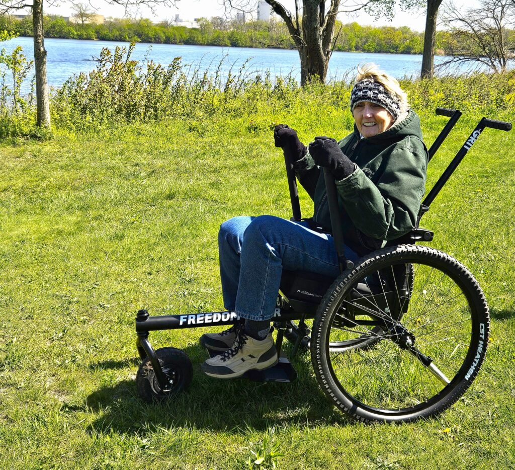 Kim Kosmatka of Mokena was the first person to test the new GRIT Freedom Chair at the Forest Preserve District of Will County’s Four Rivers Environmental Education Center in Channahon. She said she loved that she could travel over grass, roots and mud and feel secure while doing so. The wheelchair is available for public use at no cost. (Forest Preserve photo by Cindy Cain)