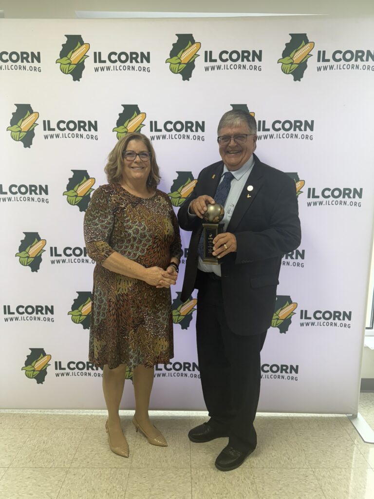 Schneidewind at wife Anita pictured as he accepts the "World of Corn" award from the Illinois Corn Growers Association.