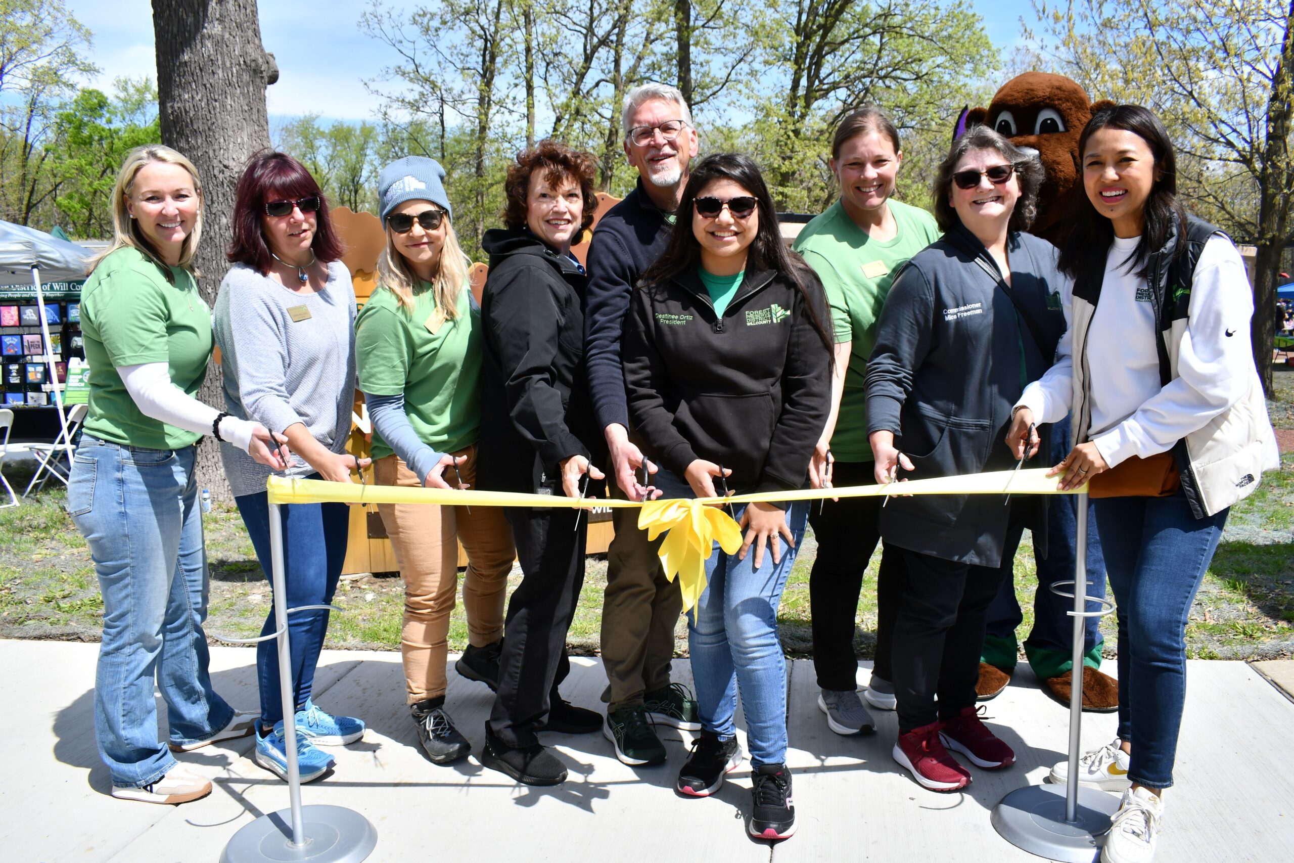 Officials gather for a ribbon cutting at the Forest Preserve District of Will County’s Hidden Oaks Nature Center in Bolingbrook on May 3. From left to right are Forest Preserve District Deputy Director Tracy Chapman, Commissioner Dawn Bullock, facility supervisor Angie Trobaugh, Commissioner Jackie Traynere, Executive Director Ralph Schultz, Board President Destinee Ortiz, visitor services Director Lydia Pond, Board Secretary Mica Freeman, Forest Preserve mascot Willy Woodchuck, and Commissioner Elnalyn Costa. (Photo by Forest Preserve staff)