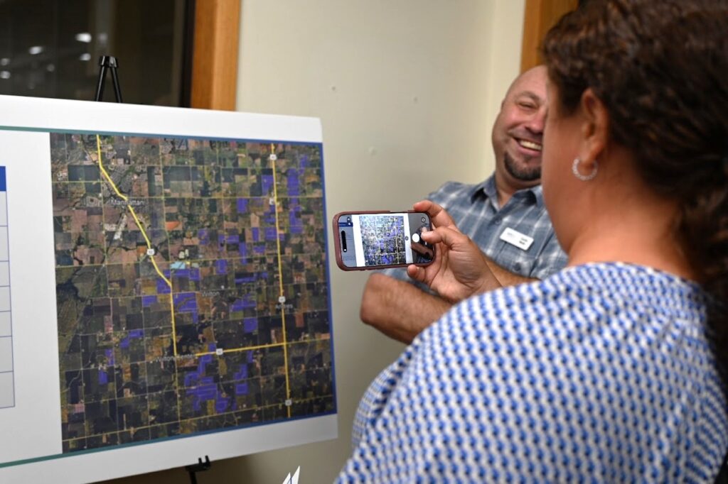 Curtis Wells, Land Manager for Earthrise Energy, explains company's 5,400-acre solar farm plan as an attendee at a recent open house in Manhattan takes a photo. There were handouts at the open house to share, but no maps. A separate open house was held the following day for another of the company's solar farm plans in Crete. (Photo by Stephanie Irvine)
