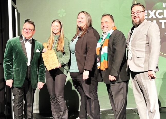 Heritage Corridor Destinations staff and board accept award on stage with Deputy Director Daniel Thomas of the Illinois Office of Tourism, from left, Daniel Thomas, Claire Mierzwa, Lauren Las, Bob Navarro and Greg Peerbolte.