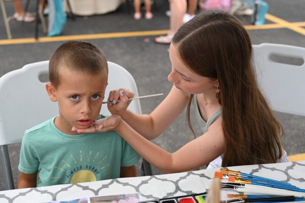 Addy Brown paints customer John Boyle’s face at Manhattan's Young Entrepreneurs Market.(Photo by Stephanie Irvine)