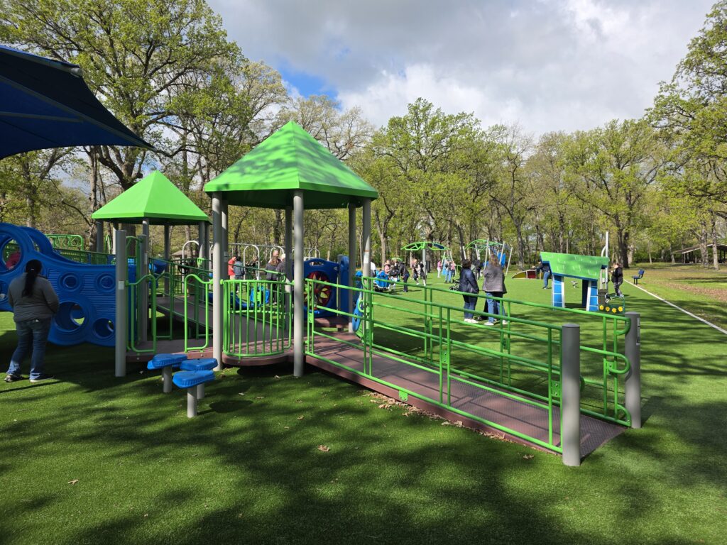 At the heart of the large, rectangular play space at Joliet Park District's new inclusive playground -- the largest of its kind in the state -- is an accessible, ramped GameTime play structure featuring multiple slides, varied climbers -- including a naturalistic rockscape -- and integrated shade to support comfort and usability throughout the day.
