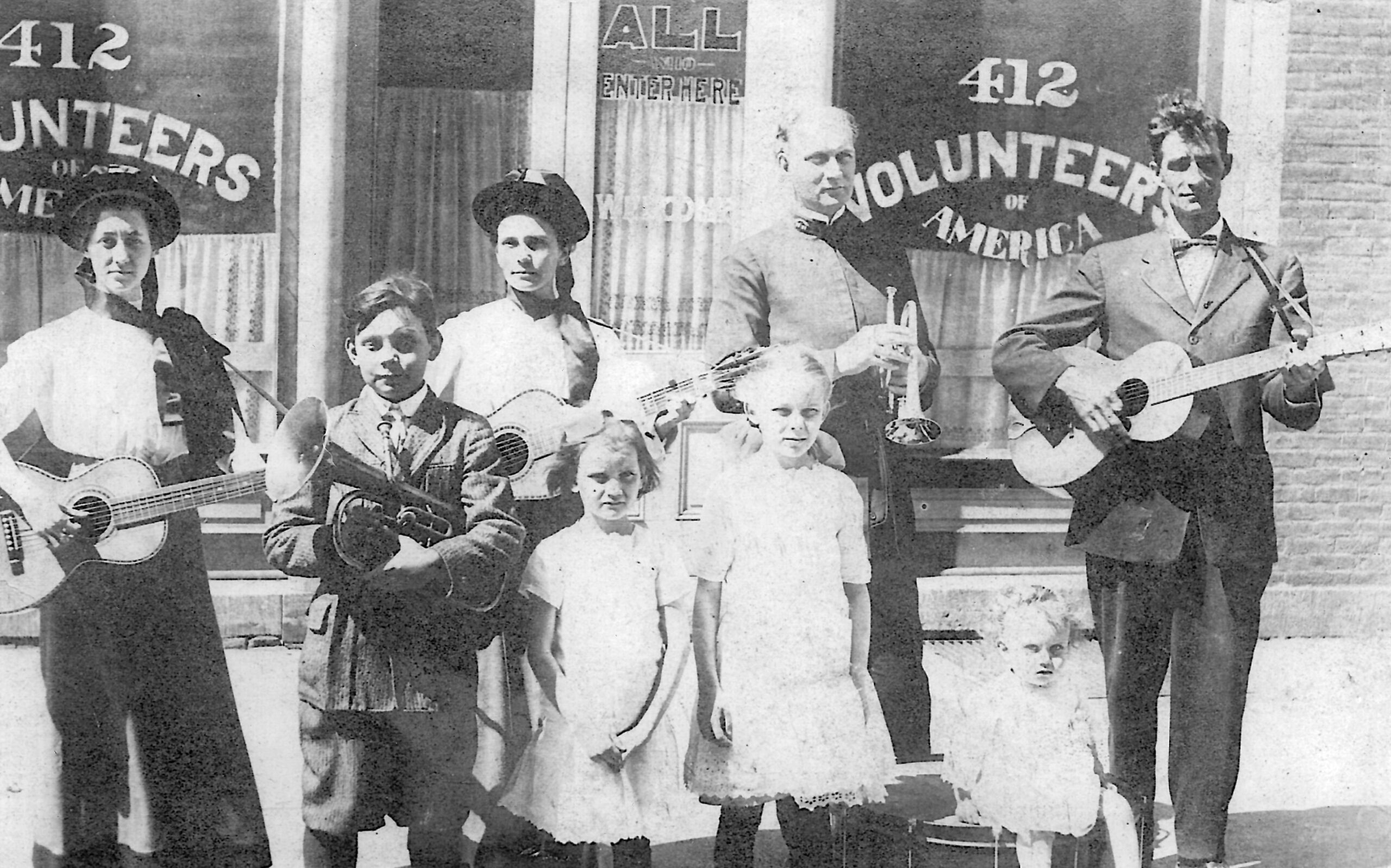 Dick Attaway shares this photo of his wife Gwen's Grandmother, Mary Pool and Grandfather, George Pool. The Pools operated The Volunteers of America mission in Joliet, from the early 1900s up to the 1950s.Their facility was located at 412 S. Chicago St. Mr. and Mrs. Pool visited farms in the Will County, area asking for donations of poultry, produce, etc. to provide meals at the mission and to distribute food to the needy. Mary and George are in the background their three children in front. The two guitar players and baby are unidentified. Gwen can remember her grandmother slaughtering chickens in the backyard, in preparation of the evening meal. They fed anyone that came to their door, but asked that in return they perform some type of chore.